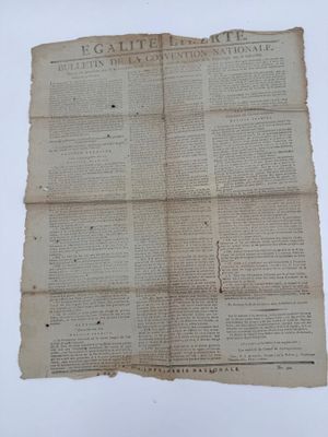 un vieux journal sur lequel est posé un bout de papier