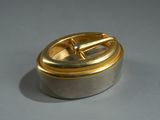 a silver and gold container with a handle on a table