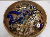 a wooden bowl filled with lots of jewelry on a table
