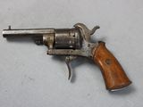 an old revolver with a wooden handle on a white surface