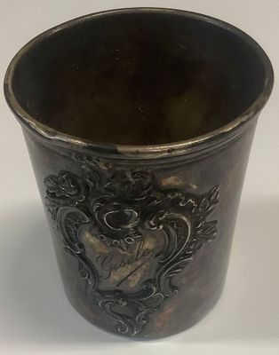 a silver cup with a design on it on a white surface