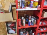 a red shelving with many cans of paint on it