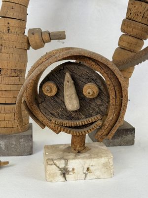 a sculpture of a face made out of wood on a stand