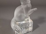 une figurine en verre représentant un chat assis sur une boîte