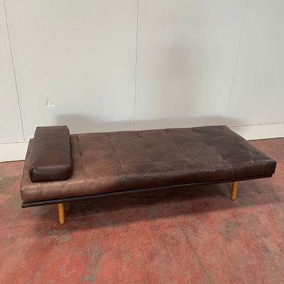 un futon en cuir marron sur lequel est posé un oreiller