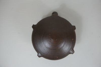 un pot marron posé sur une table blanche, sur fond blanc