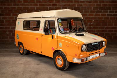 an orange and white van parked in front of a brick wall