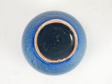 a blue vase with a brown rim sitting on a white surface