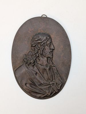 an old bronze medallion of a man with long hair and a beard