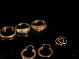 several different types of gold rings on a black surface