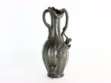 un vase en argent posé sur une surface blanche