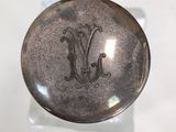a small silver object with a monogram on it