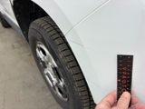 a person holding a ruler next to a white car
