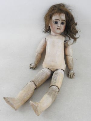 une poupée en bois assise par terre sur un fond blanc