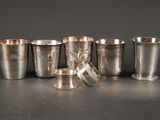 Plusieurs coupes et tasses en argent sont alignées sur une table
