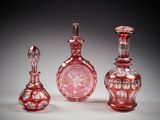 three red glass vases sitting next to each other on a white surface
