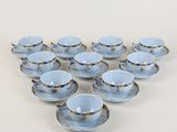 six tasses et soucoupes sont disposées en forme de cœur sur une surface blanche