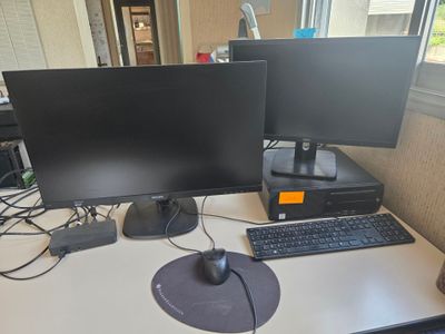 two computer monitors and a keyboard on a desk
