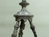a metal tripod that has a bird on top of it