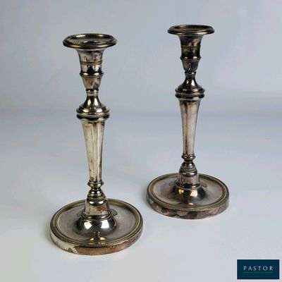 deux bougeoirs en argent posés sur une table