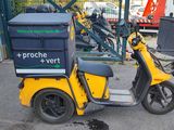 a scooter with a box on the back parked in front of a building