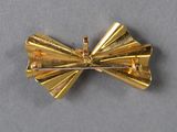 a gold bow brooch on a gray surface