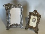 two silver picture frames sitting next to each other on a table