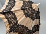 un parapluie ouvert orné de dentelle noire sur fond blanc