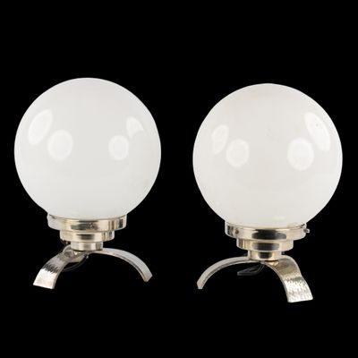 une paire de lampes de table en verre blanc en forme de globe, montées sur des pieds en métal