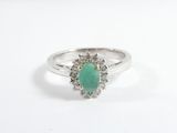 gros plan d'une bague avec une pierre verte entourée de diamants
