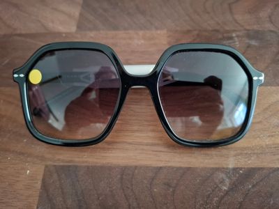 des lunettes de soleil posées sur une table en bois, avec une personne en train de les prendre en photo