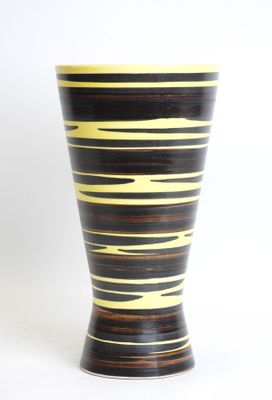 black and yellow striped vase sitting on a white surface
