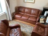 two brown leather couches and a chair in a living room