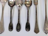 several spoons, forks and spoons are lined up against a white wall