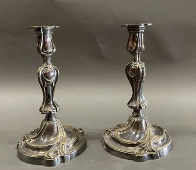 paire de bougeoirs anciens en argent posés sur un socle, sur fond gris