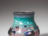 a colorful vase with birds on it sitting on a table