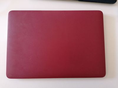 a red laptop computer sitting on a table next to a keyboard