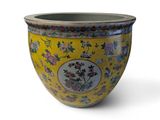 un vase jaune orné de fleurs sur fond blanc