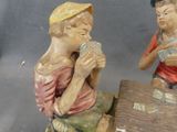 two figurines of two men sitting on a log