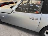 a silver car with a black top parked in a parking lot