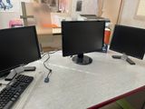 three computer monitors sitting on a desk with a keyboard and mouse