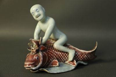 a figurine of a boy riding a fish