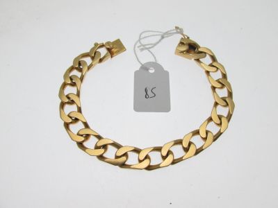 gros plan d'un bracelet en chaîne en or sur une surface blanche