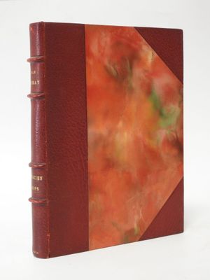 an old book with a red cover sitting on top of a white table