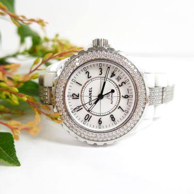 a close up of a watch with a flower in the background