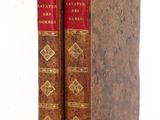 two old books sitting on top of each other on a white surface