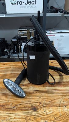 a black canister with a remote on a wooden table
