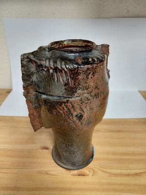 a brown vase that is sitting on a wooden table