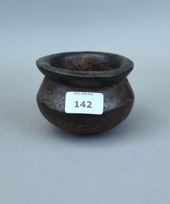 un petit vase noir sur lequel est accrochée une étiquette blanche