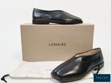 Le mocassin noir se trouve à côté d'une boîte et d'un sac blanc